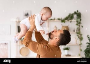 padre che gioca con neonato a casa