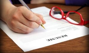 persona che scrive un curriculum con penna