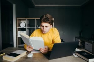 studente concentrato con libri e laptop